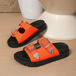Hochwinkel-Detailansicht lebhafter orangefarbener Plateausandalen mit Silberschnallen.