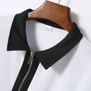 Nahaufnahme des schwarzen Kragens und Metallreißverschlusses an einem weißen Polohemd