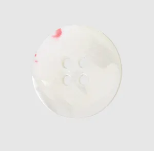 Close-up of high-quality white top shell button with unique red patterns for clothing.