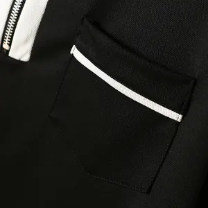 Detailaufnahme der Brusttasche und des silbernen Reißverschlusses am schwarzen Polohemd