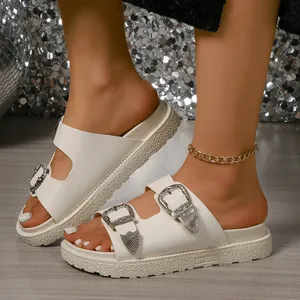Nahaufnahme weißer Plateau-Sandalen mit stylischen Western-Schnallen aus Metall und dicker Sohle