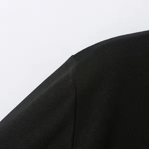 Nahaufnahme des schwarzen, atmungsaktiven Stoffs und der Schulternaht eines Herren-Poloshirts