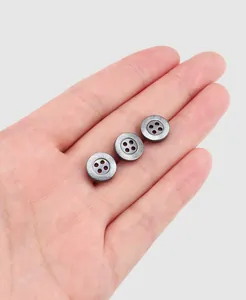 Gros plan de trois boutons de chemise gris avec motif de labyrinthe sur une paume
