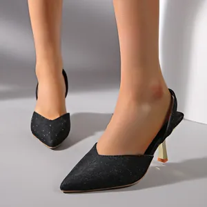 Close-up of elegant black glitter pointed-toe slingback pumps with gold stiletto heels
