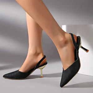 Detail of French-style black glitter slingback heels with gold kitten heel for women.