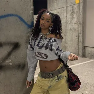 Camiseta corta gris con hombros descubiertos y letras, usada por una modelo