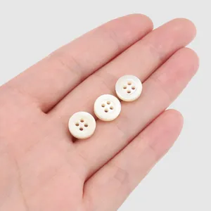 Set of premium white shell shirt buttons featuring engraved Greek key pattern shown on palm
