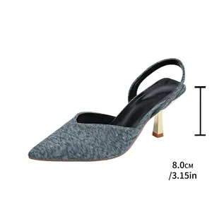 Detail view of the 8cm gold stiletto heel on a pointed-toe grey textured slingback sandal.