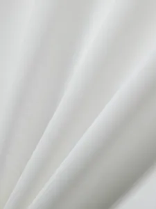 Macro view of the breathable white knit fabric detail for summer polo shirt texture.