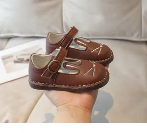 Detailed view of brown toddler Mary Janes featuring cute embroidered cat face design