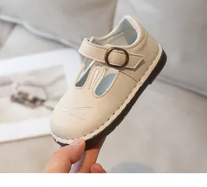 Close-up detail of a beige toddler girl leather shoe with cute cat face embroidery and buckle