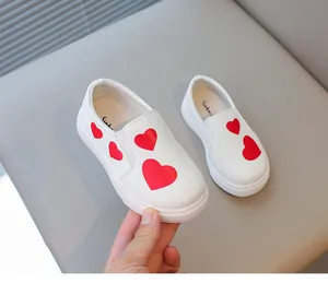 Detail view of white toddler slip-on shoes featuring cute red heart patterns and soft soles