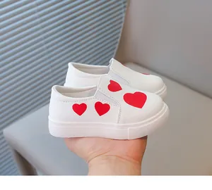 Close-up of white toddler slip-ons featuring vibrant red heart patterns on the side.