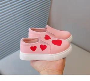 Close-up view of pink toddler girls' casual slip-on shoes with cute red heart prints