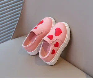 Close-up of pink girls' slip-on shoes featuring vibrant red heart patterns and soft white soles