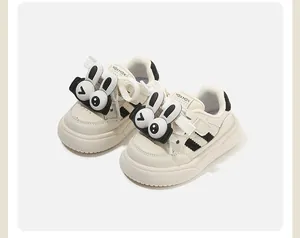 Dettaglio di scarpe da ginnastica per neonati color panna con ciondoli a forma di coniglio