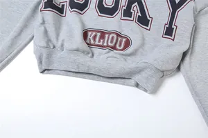 Detalle del dobladillo acanalado y estampado 'KLIOU' en sudadera corta gris.