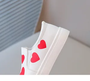 Close-up of red heart patterns on white girls' leather shoes
