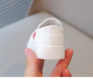 Detailed view of the white toddler girl's shoe showing heel stitching and red heart