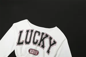 Detalle del diseño de la camiseta blanca de manga larga con estampado de letras LUCKY