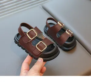 Detailed view of brown children's open-toe sandals with golden buckles and thick black soles