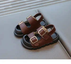 Close-up of brown children's sandals featuring elegant gold adjustment buckles