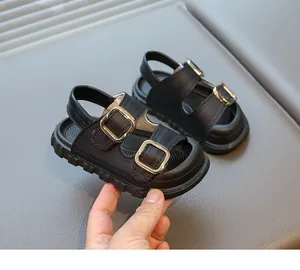 Close-up of black children's sandals with double gold buckles and thick anti-slip sole