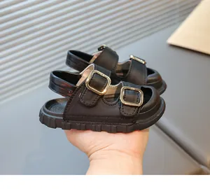 Detail shot of black children's sandals featuring dual gold buckles and a thick sole.