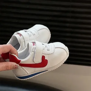 Close-up detail of white and red toddler walking shoes featuring secure velcro straps