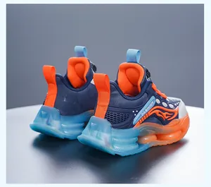 Détail de baskets de sport pour enfants bleu marine et orange à semelles translucides.