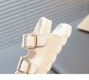Close-up detail of white children's sandal showing metal buckles and fine stitching