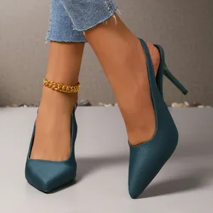Elegantes Detail von petrolfarbenen Satin-Pumps mit spitzer Zehenpartie und goldener Fußkette