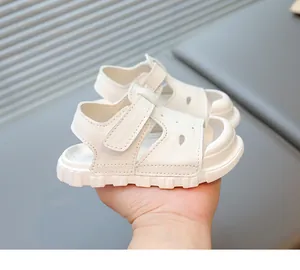 Close-up view of white soft-soled baby sandals featuring a hook and loop strap design
