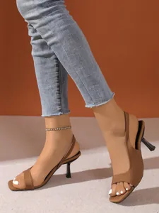 Κομψά καφέ πέδιλα slingback με ψηλό τακούνι φορεμένα με ανοιχτόχρωμο τζιν παντελόνι