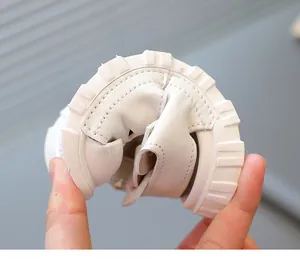Close-up view of white toddler sandal being flexed to demonstrate its soft and flexible sole