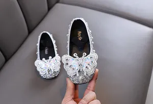 Nahaufnahme von silbernen Mädchen-Prinzessin-Glitzerschuhen mit großem Perlen-Schmetterling.