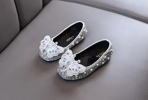 Detail von funkelnden silbernen Prinzessinnenschuhen für Mädchen mit Schmetterlings-Applikation.