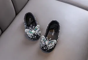 Nahaufnahme von schwarzen Mädchen-Prinzessin-Schuhen mit funkelndem Strass-Schmetterling