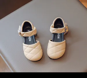 Dettaglio di sandali da principessa trapuntati beige per bambine con fibbia in metallo