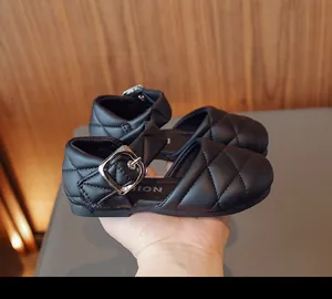 Vista macro che mostra la trama della pelle trapuntata e la fibbia regolabile di queste scarpe da bimba