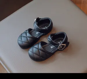 Primo piano di scarpe Mary Jane trapuntate nere per bambina con fibbia argento.