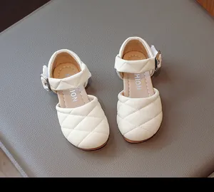 Dettaglio sandali trapuntati panna per bambini con elegante fibbia in metallo