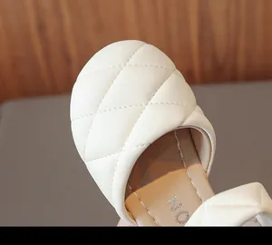 Primo piano di scarpe in pelle trapuntata crema per bambina con cuciture a diamante
