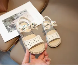 Detalle de sandalias beige para niña con lunares y lazo de flores