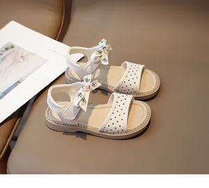 Primer plano de sandalias de princesa blancas con lunares para niña y lazo floral