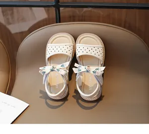 Primer plano de sandalias de princesa blancas con lunares para niña y lazo bordado