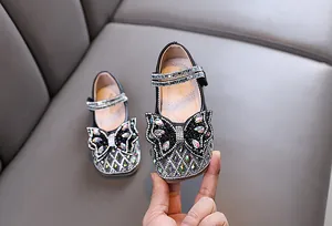 Vista detallada de zapatos de cuero negro para niña con lazo de mariposa y pedrería