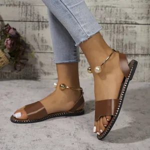 Gros plan de sandales plates marron avec bride de cheville en perles et bout ouvert