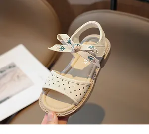 Primer plano de sandalias crema de lunares para niña con lazo de flores