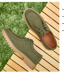 Detailed view of men's olive green suede leather wallabee shoes on wooden surface